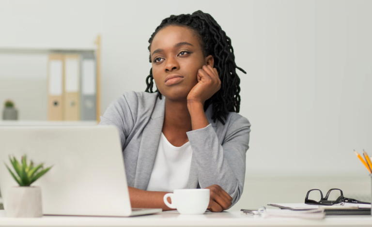 Boring Job. Depressed Black Office Girl Sitting At Laptop Touching Chin In Office. Empty Space