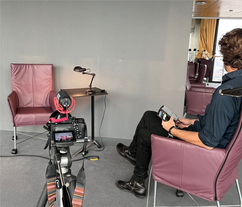 A set up for an interview with red chairs and a camera.